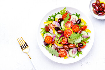 Vegan vegetable salad with olives, tomato, paprika, cucumber and onion, healthy mediterranean food. White background, top view