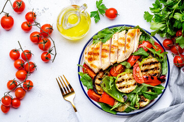 Healthy eating salad with grilled paprika, zuccini and chicken, cherry tomatoes and lettuce, white background, top view