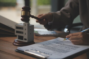 Real Estate Law, Home Insurance, property Tax, Auction and Bidding concepts. small toy house model with gavel justice hammer on desk in courthouse.