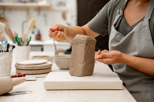 Wire clay cutter to cut clay from a large block. Cutting off the necessary piece of clay before forming a pottery product. Learning how to cut clay on ceramics workshop.