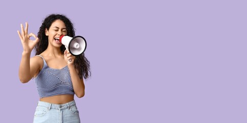 Obraz premium Young African-American woman with megaphone showing OK on lilac background with space for text