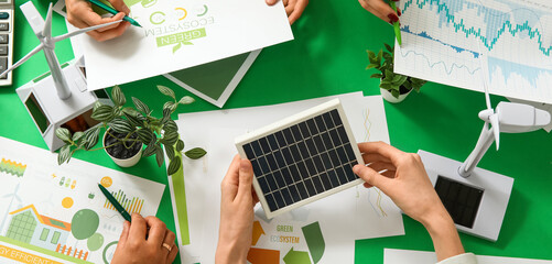 Business team with wind turbine models and solar panel during meeting in office. Green energy concept