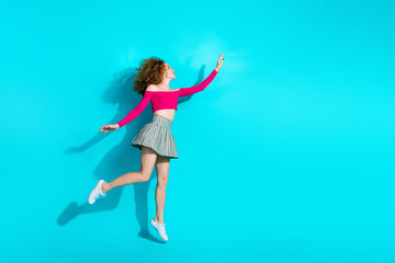 Full size photo of pretty young girl jump empty space ad wear top isolated on teal color background