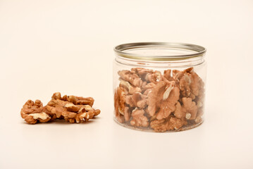 Walnuts in a plastic jar on a white background.