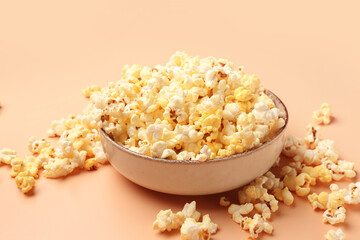 Bowl with crispy popcorn on beige background