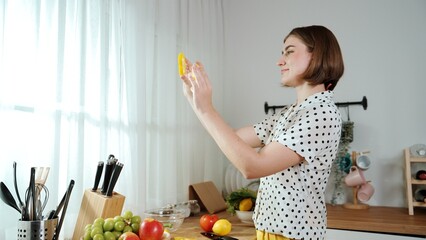 Obraz premium Happy mother chopping at vegetable or making salad and pose at camera. House keeper prepare fresh ingredients while looking at camera. Smart mom cooking at modern kitchen with kitchenware. Pedagogy.