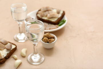 Shots with cold vodka and snacks on beige background