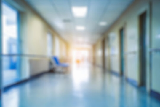 blurred of background. interior of a modern hospital with an empty long corridor. waiting room for patients and families between the corridor with bright white lights. treatment rooms and patient room