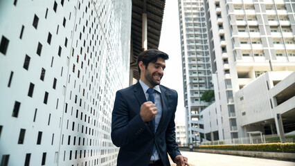 Skilled business man dancing with joyful while walking in city street. Project manger receive a good news, getting promotion, getting a successful job while express feeling of overjoy. Exultant.