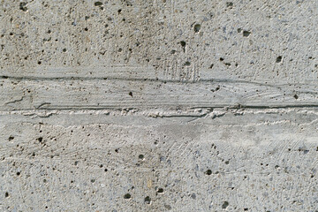 Oberfäche aus Beton mit Löchern  und Rissen mit eingeschlossenen Kiesel Steinen
