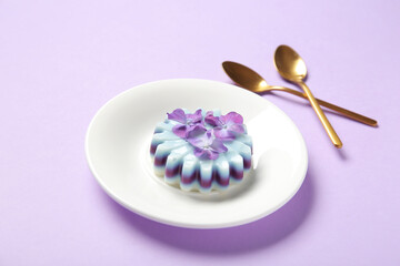 Plate of panna cotta with beautiful hydrangea flowers on lilac background