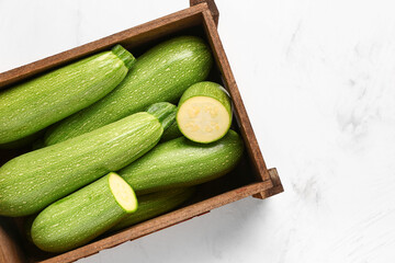 Wooden box with fresh green zucchini on white background