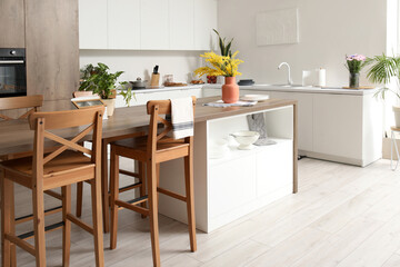 Interior of modern kitchen with white counters and island table