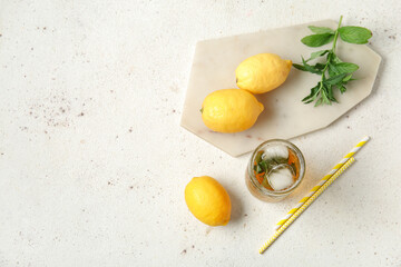 Glass of ice tea and board with lemons on white background