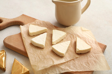 Board with triangles of tasty processed cheese on light background, closeup