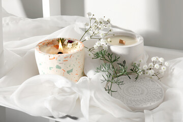Gypsophila flowers and burning candle on table in room, closeup