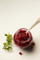 A small jar of lingonberry wild berries on a white background, top view