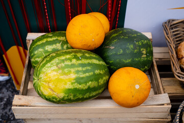 A sturdy wooden crate that is completely filled with fresh, juicy watermelons and assorted melons, ready for transporting or selling at a market or grocery store, showcasing natures bounty