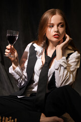 Young woman with glass of wine playing chess on floor