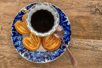 Cup of coffee, heart shaped cookies for tasty breakfast over wooden background.
