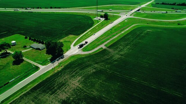RGN trailer Semi truck with oversize load in Indiana, USA on countryside roads. Overview aerial.