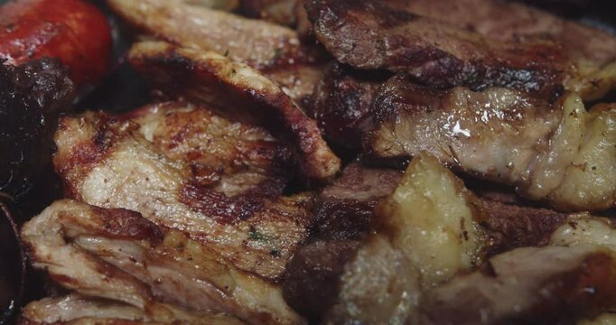 Beautiful slow motion close-up shot of a barbecue plate with meat, sirloin, steak and sausages, potatoes inside a restaurant kitchen.