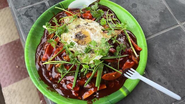 Chicken Schezwan Noodles or Hakka or Chow Mein with egg poach in green plate.