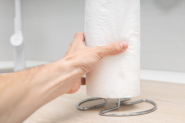man changing a paper towel in the kitchen, close-up. paper towel holder. roll of paper towel in the kitchen