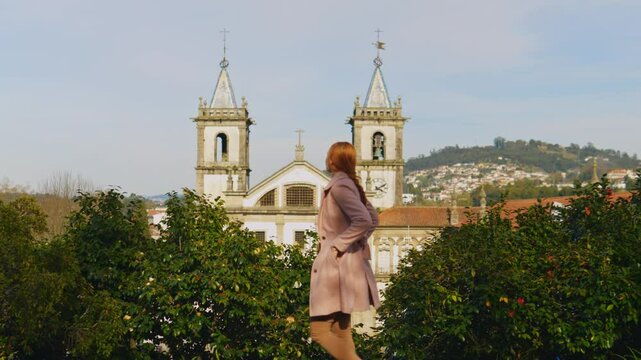 Stunning 4k footage of a young white caucasian ginger girl posing in front of the Abade Pedrosa Municipal Museum and the Monastery of St. Benedict (Sao Bento) in the Portugal city - Santo Tirso.