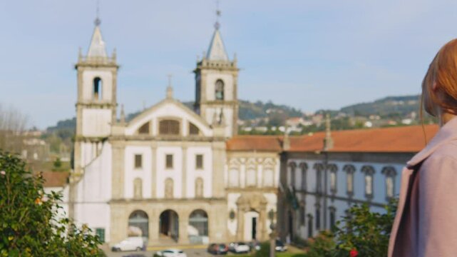 Stunning 4k footage of a young white caucasian ginger girl posing in front of the Abade Pedrosa Municipal Museum and the Monastery of St. Benedict (Sao Bento) in the Portugal city - Santo Tirso.