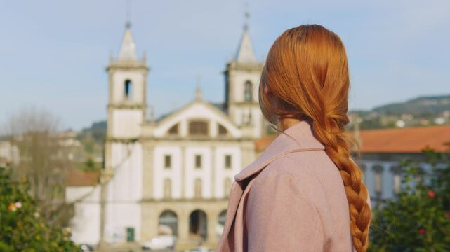 Stunning 4k footage of a young white caucasian ginger girl posing in front of the Abade Pedrosa Municipal Museum and the Monastery of St. Benedict (Sao Bento) in the Portugal city - Santo Tirso.