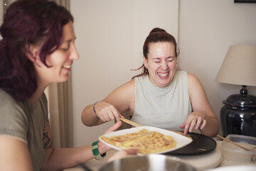 Two women are laughing and eating a dessert