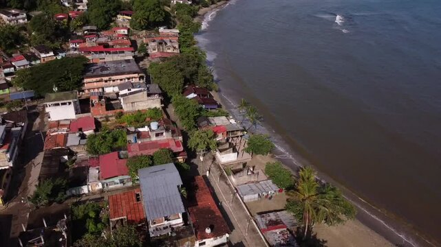 Tilted aerial shot of crashing waves and coastal buildings.