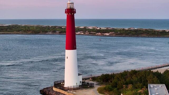 A 70mm drone shot of the Barnegat Lighthouse, located on the northern tip of Long Beach Island, New Jersey. The camera orbits and pans up, slowly revealing the lighthouse and the surrounding bay.