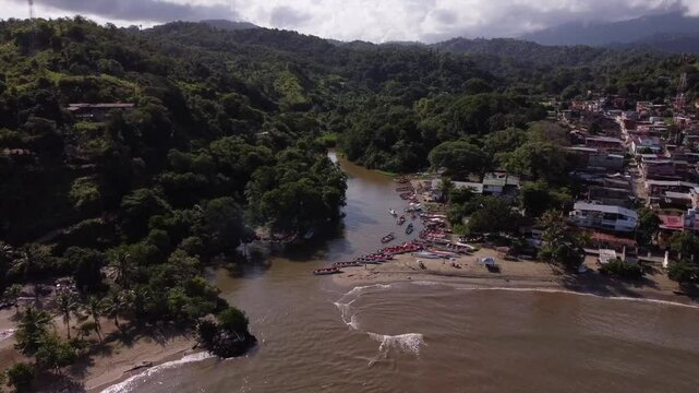 Aerial view of a bustling river estuary in the Caribbean, with boats and coastal buildings.