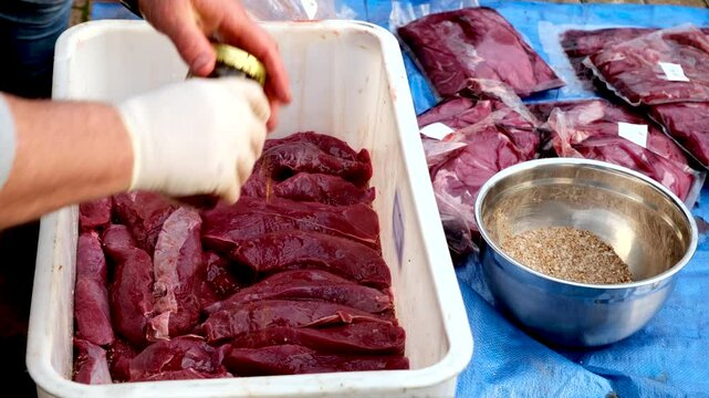 Raw venison steaks stacked and cured with vinegar and mixed herbs spices, biltong making process South Africa snack delicacy