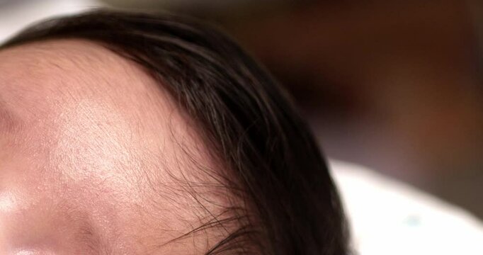 Close-up shot of a newborn baby's forehead while it is sleeping so soundly inside her soft and comfortable bed.