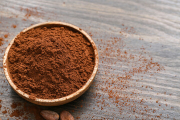 Bowl with cocoa powder on wooden background