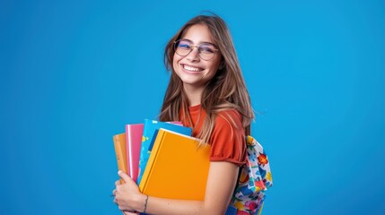 Cheerful young woman with glasses, holding educational books, vibrant cobalt blue background, studio photo