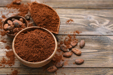 Bowls with cocoa powder and beans on wooden background
