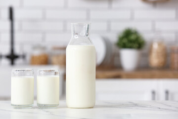 Glasses and bottle of fresh milk on white table