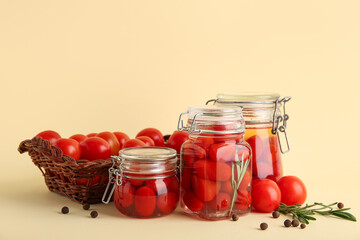 Jars of pickled tomatoes with rosemary and peppercorn on yellow background