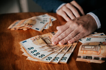 Obraz premium Man counting euro banknotes. Businessman counting money on wooden table.