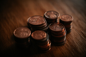 Stacks of coins on a wooden table. Shallow depth of field.