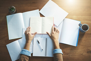 Obraz premium Hands, paper and notebook in top view on desk for planning, writing and brainstorming ideas in office. Person, notes and books from above on table for journal, startup inspiration and business pitch
