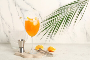 Decorative podium with glass of Aperol spritz cocktail and palm leaf on white background