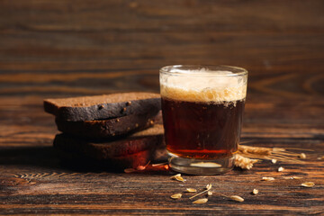 Glass of fresh kvass and slices of bread on wooden background
