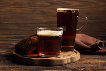 Glasses of fresh kvass and slices of bread on wooden background