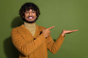 Photo portrait of handsome young guy point hold empty space dressed stylish brown garment isolated on khaki color background