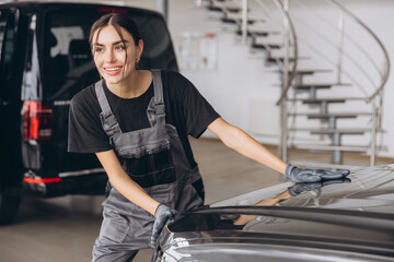 Professional female car mechanic examining, repair and maintenance under hood of car at auto car repair service. Car service.